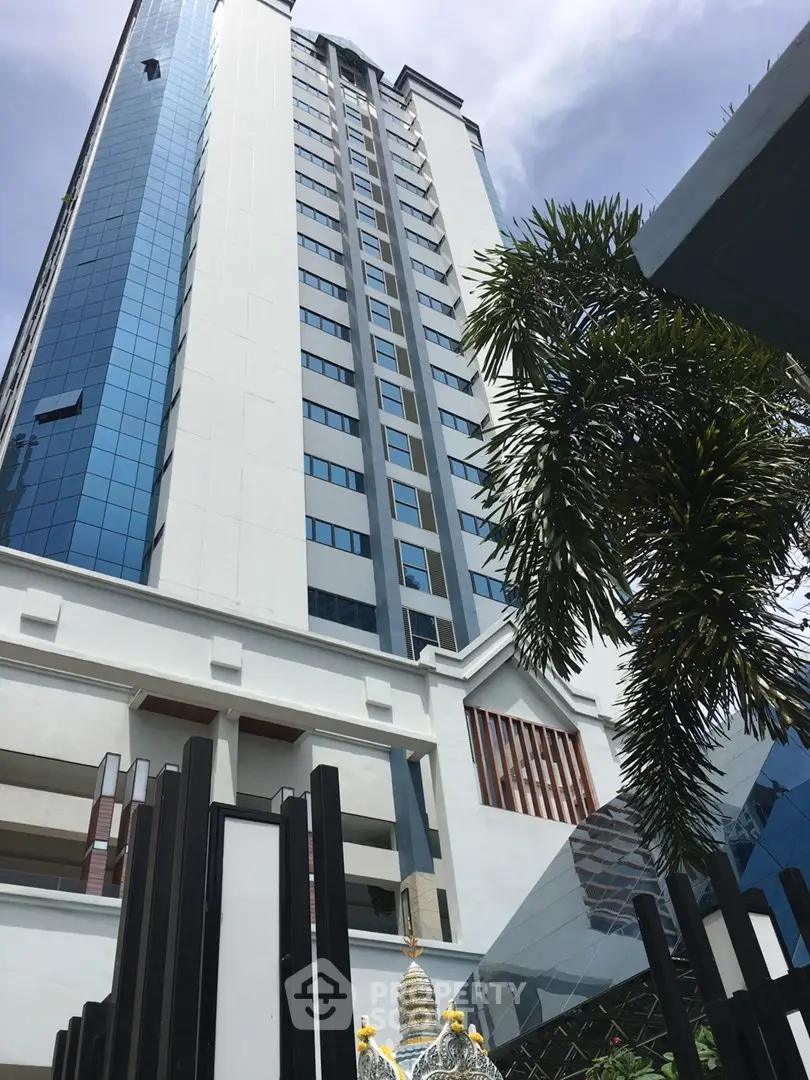 Stunning high-rise building with modern architecture and lush palm trees, perfect for urban living.