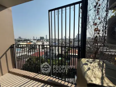 Stunning cityscape view from a cozy balcony with modern railing and lush greenery.