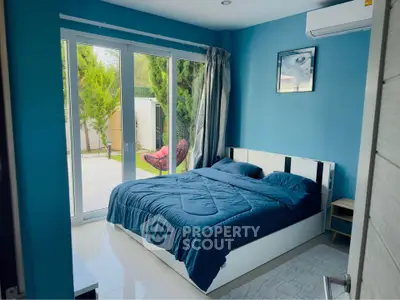 Modern bedroom with large glass doors opening to a lush garden view, featuring sleek blue decor.