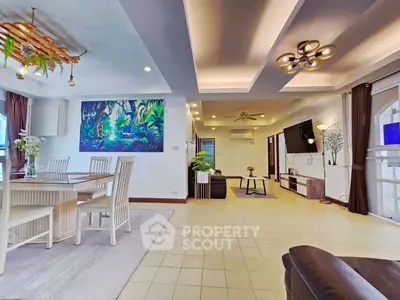 Spacious living room with modern decor and open dining area, featuring elegant lighting and stylish furniture.