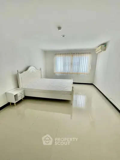 Spacious minimalist bedroom with large window and natural light