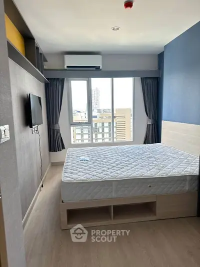 Modern bedroom with large window and city view, featuring a comfortable bed and wall-mounted TV.