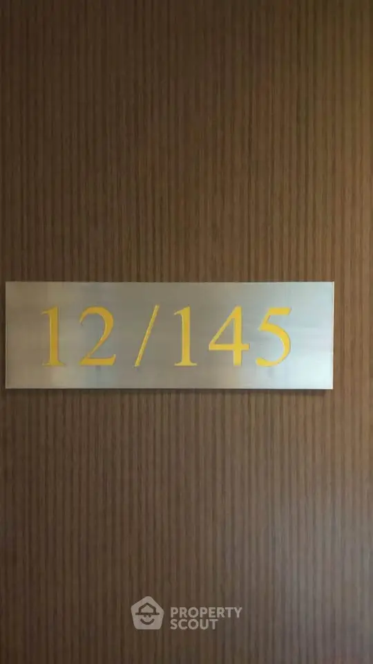 Elegant apartment door with unit number 12/145 on a sleek wooden panel.