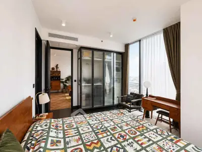 Stylish bedroom with large windows and modern decor in a high-rise apartment.