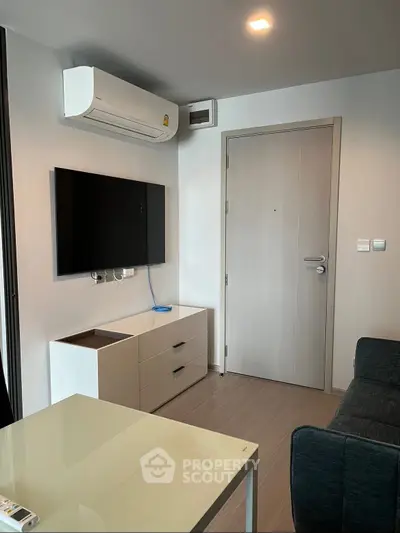 Modern living room with sleek furniture and wall-mounted TV in a cozy apartment.