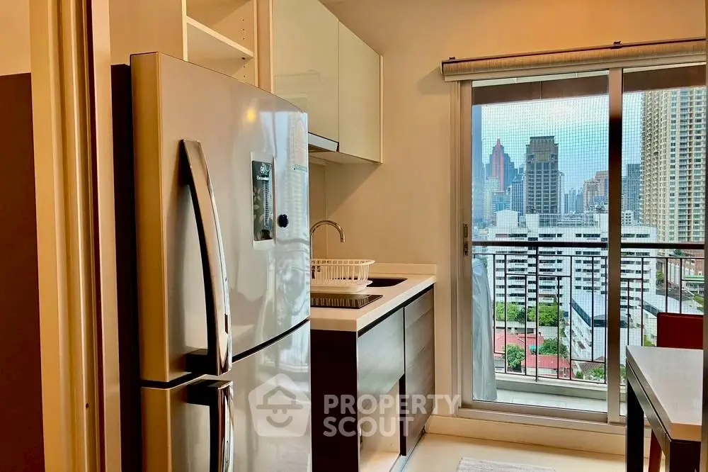 Modern kitchen with city view, featuring sleek appliances and balcony access.