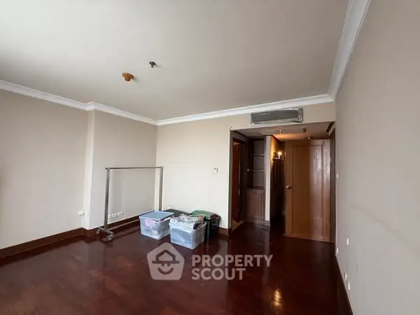 Spacious empty room with wooden flooring and neutral walls, perfect for customization.