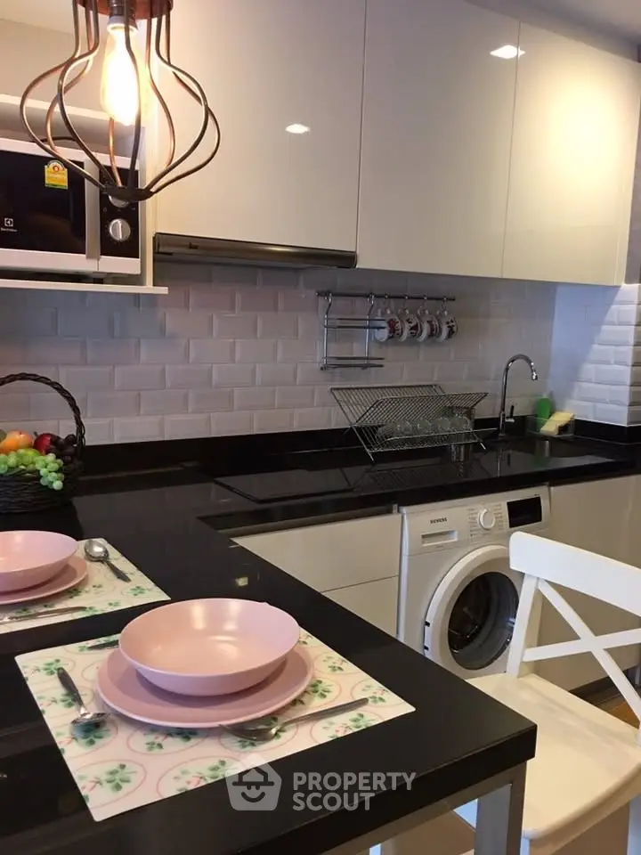 Modern kitchen with sleek black countertops, integrated appliances, and stylish lighting.