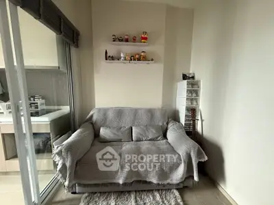 Cozy living room with plush sofa, decorative shelves, and sliding glass doors leading to a modern kitchen.