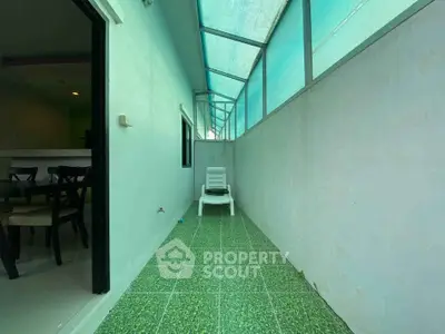 Spacious balcony with green tiled flooring and seating, perfect for relaxation.