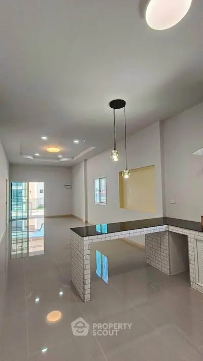 Spacious modern kitchen with sleek countertops and stylish lighting in open layout apartment.
