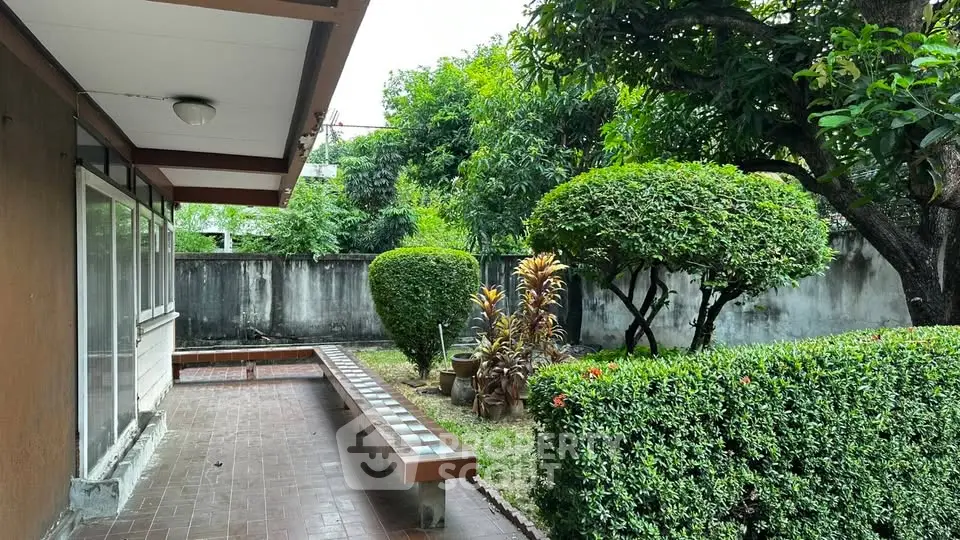 Charming garden view with lush greenery and tiled patio area in a serene residential setting.