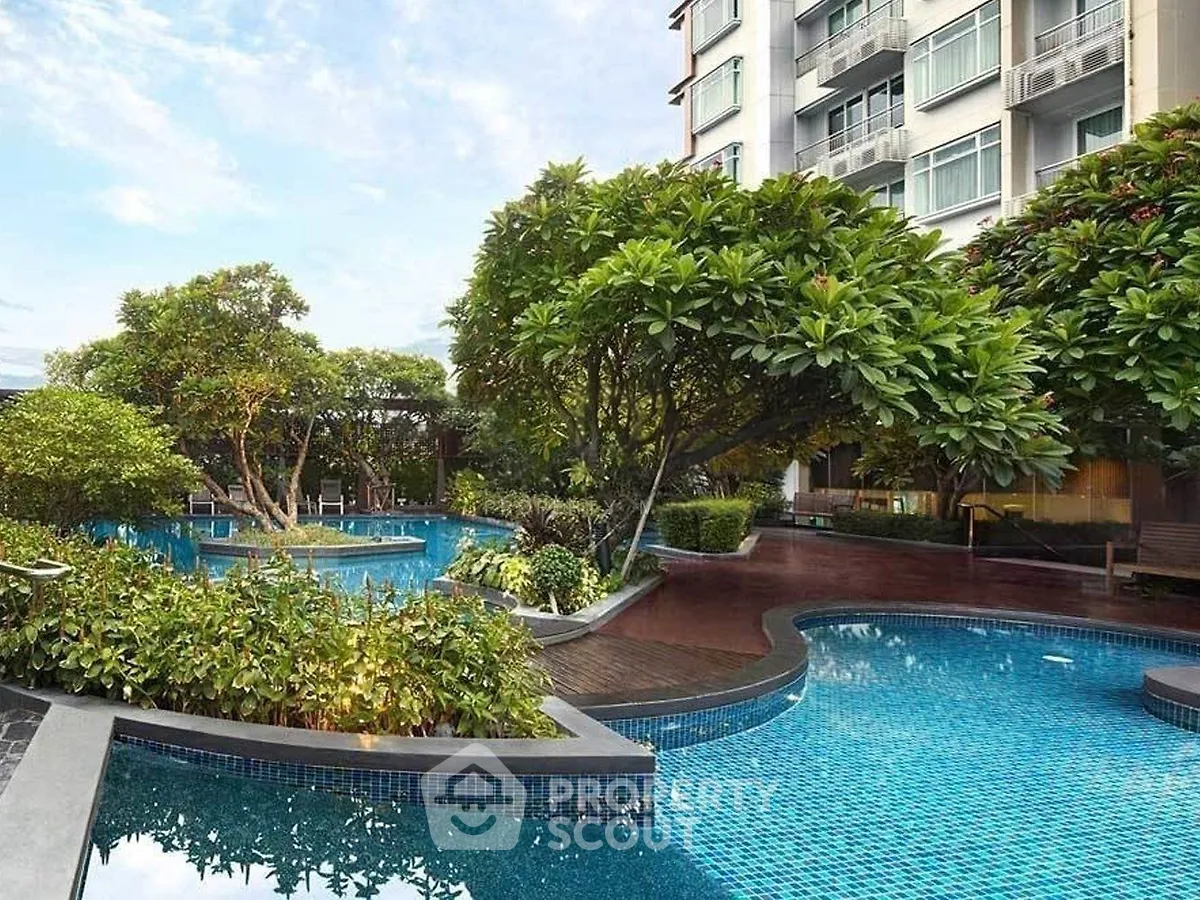 Luxurious residential building with stunning pool and lush garden view.