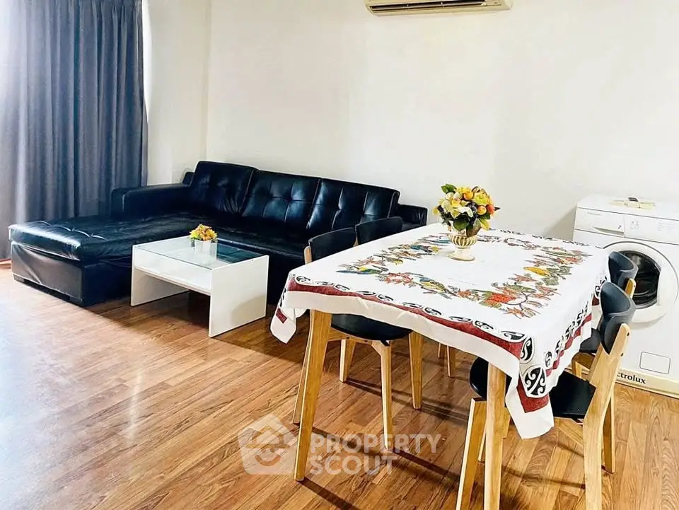 Spacious living room with modern furniture and dining area, featuring a washing machine for convenience.