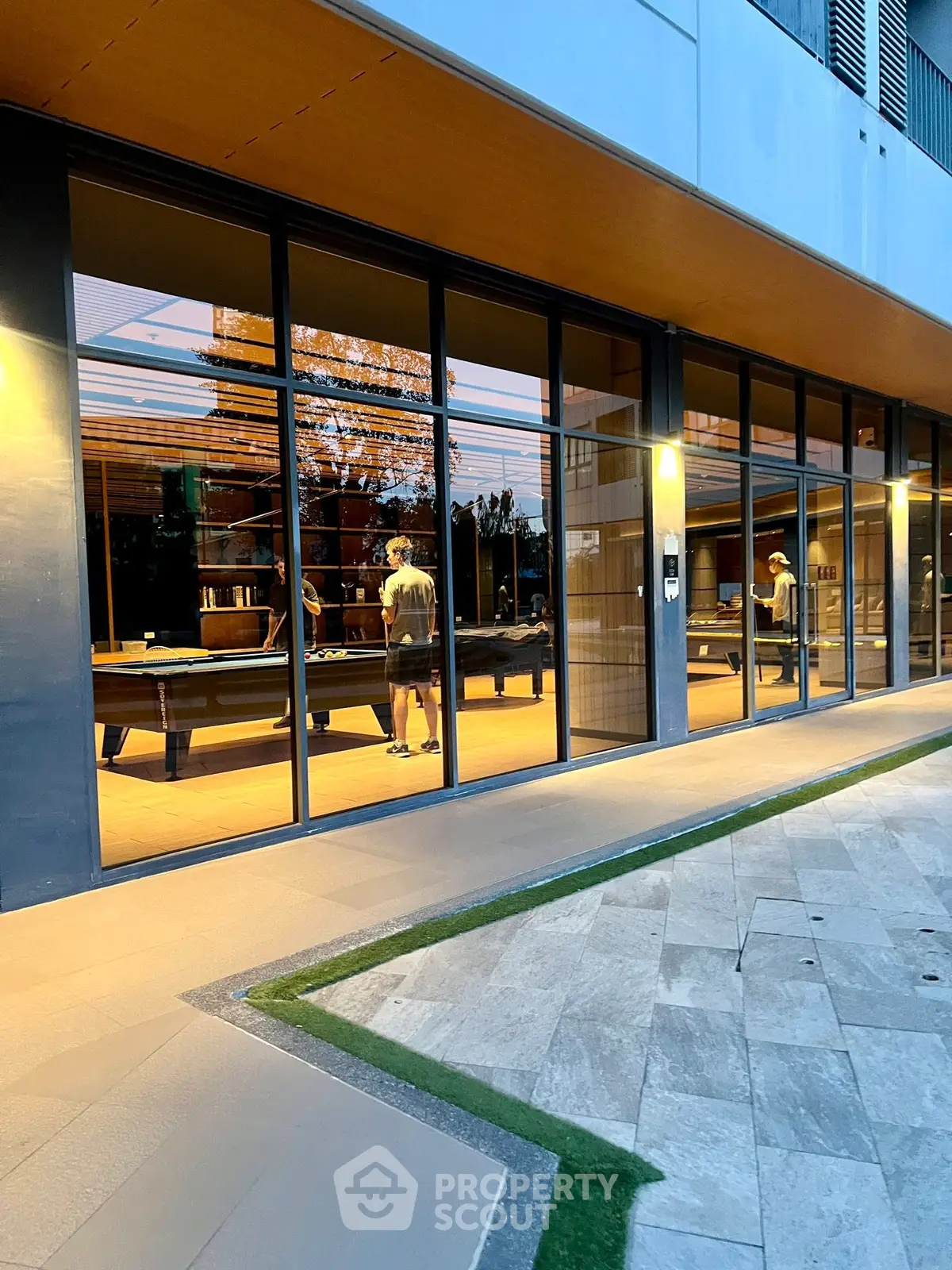 Modern building exterior with large glass windows revealing a stylish interior gym.