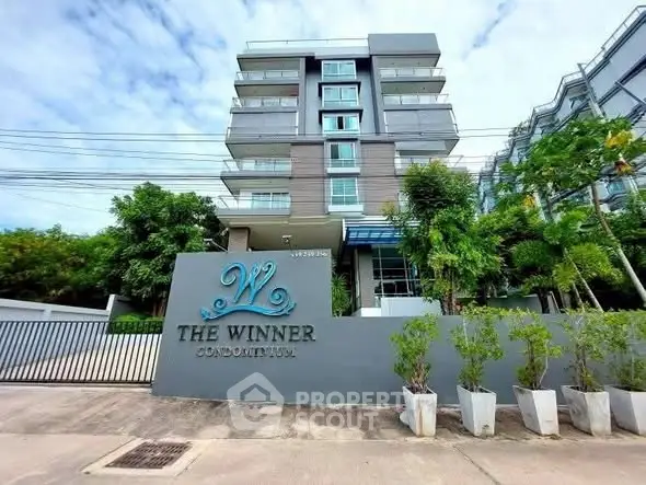 Modern condominium building with lush greenery and stylish entrance signage.
