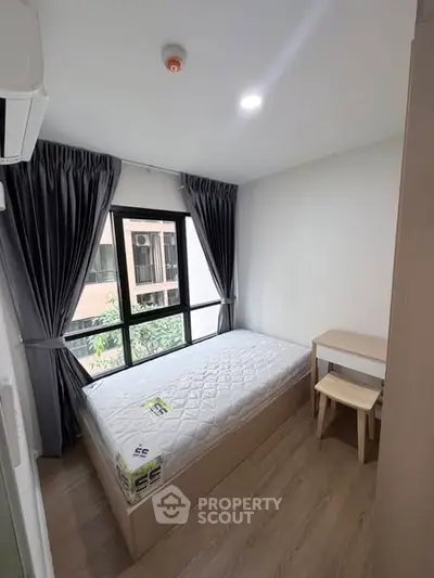Cozy bedroom with natural light and modern furnishings in urban apartment.