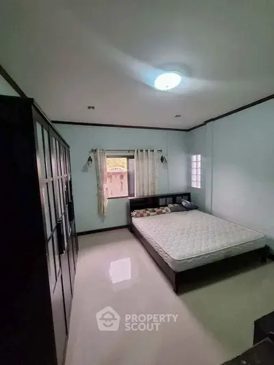 Spacious bedroom with large wardrobe and natural light, perfect for relaxation.