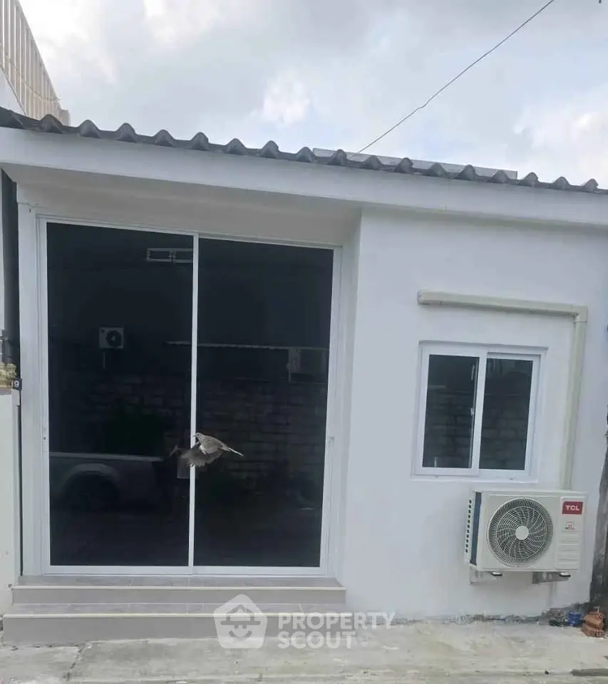 Charming small building exterior with sliding glass doors and air conditioning unit, perfect for cozy living.
