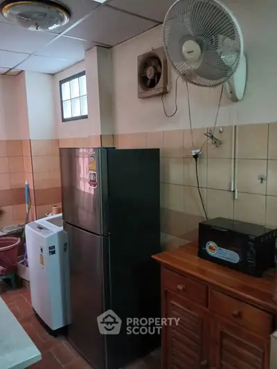 Cozy kitchen with modern appliances including fridge, washing machine, and microwave, perfect for efficient living.