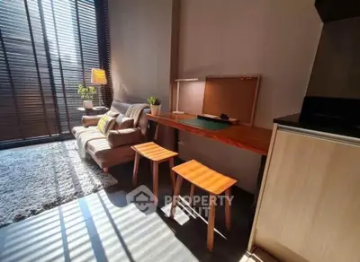 Modern living room with natural light, cozy sofa, and stylish workspace in a chic apartment.