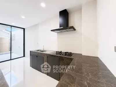 Modern kitchen with sleek black countertops and gas stove, featuring open layout and natural light.