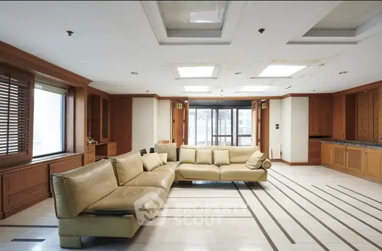 Spacious living room with modern leather sofa and large windows in luxury apartment.