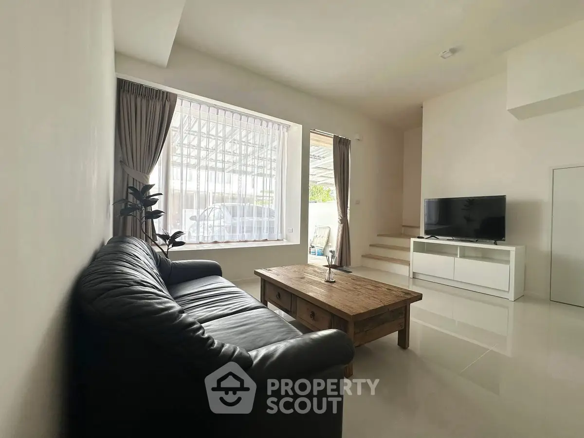 Spacious living room with leather sofa and large window, perfect for relaxation.