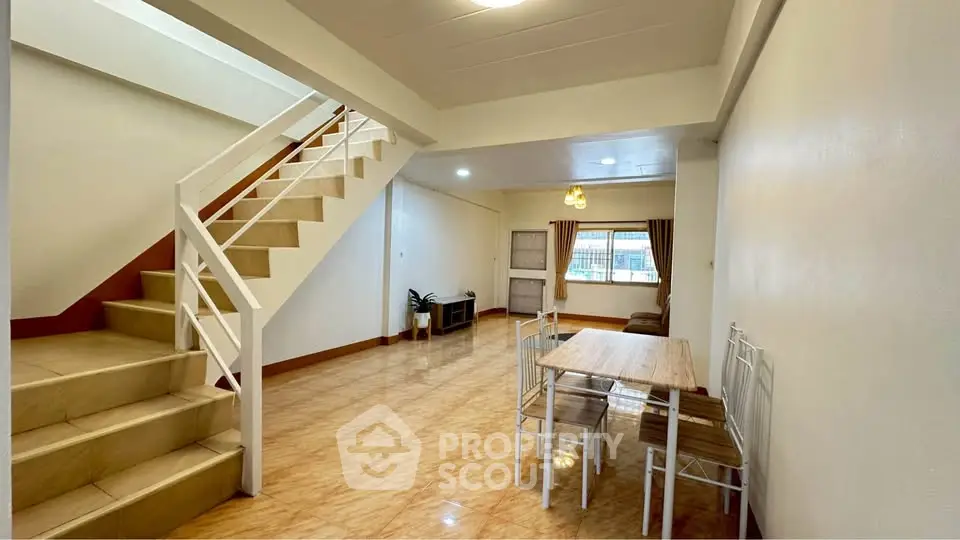 Spacious open-plan living area with modern staircase and dining set