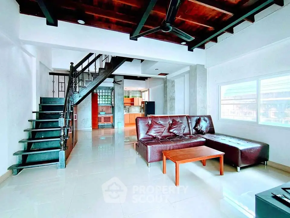 Modern living room with stylish staircase and leather sofa in open-concept loft.