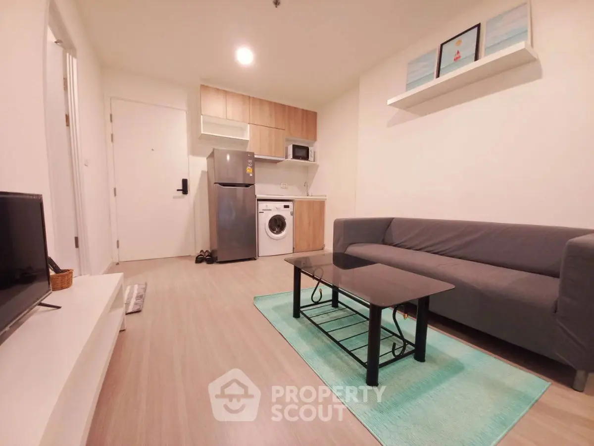 Modern living room with sleek furniture and integrated kitchen appliances in a cozy apartment.