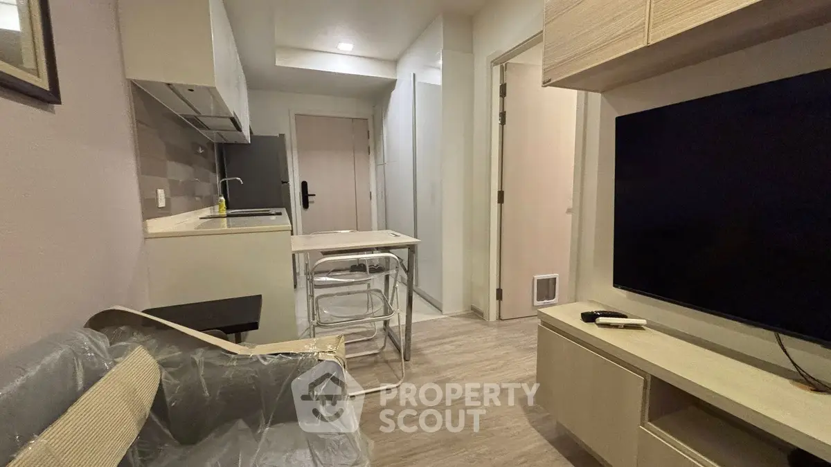 Modern compact living room with open kitchen layout and sleek furnishings.