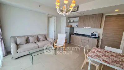 Modern living room with open kitchen, cozy seating, and elegant chandelier.