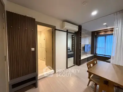 Modern living room with dining area and view into bathroom, featuring sleek design and natural lighting.