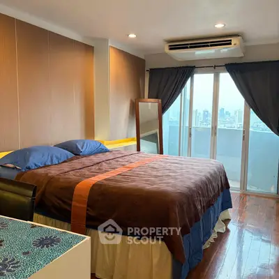 Spacious bedroom with city view and balcony access, featuring modern decor and air conditioning.