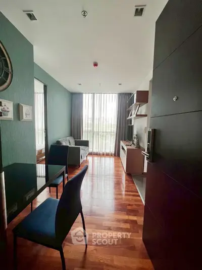 Modern living room with wooden flooring, stylish furniture, and large window for natural light.