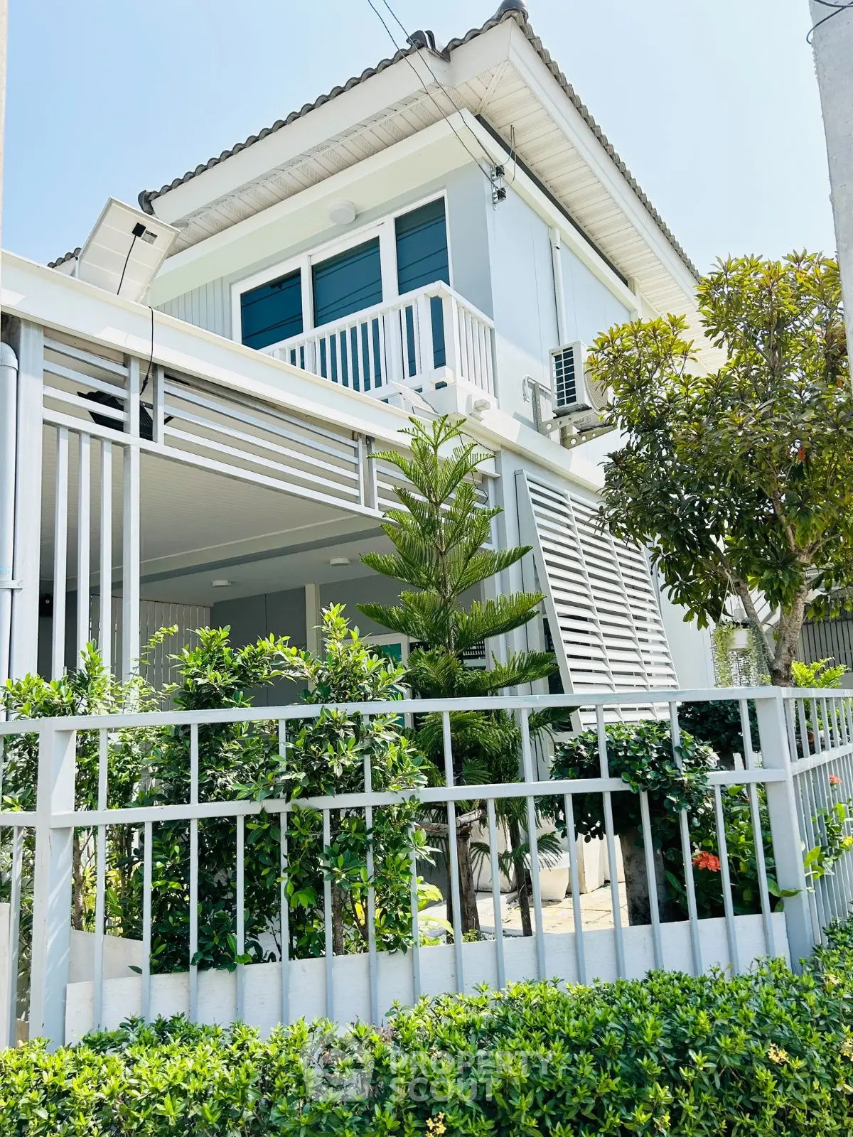 Charming modern two-story house with lush garden and balcony in a serene neighborhood.