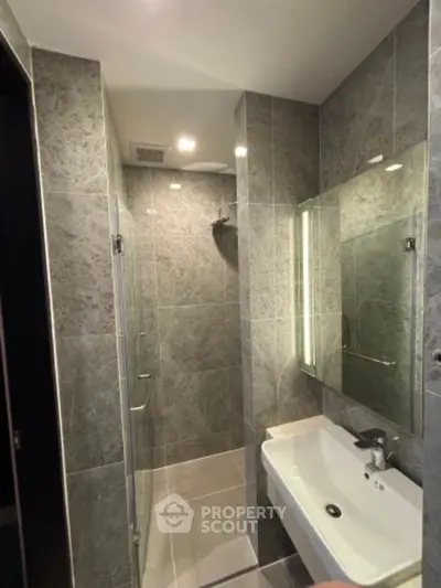 Modern bathroom with sleek gray tiles and glass shower enclosure
