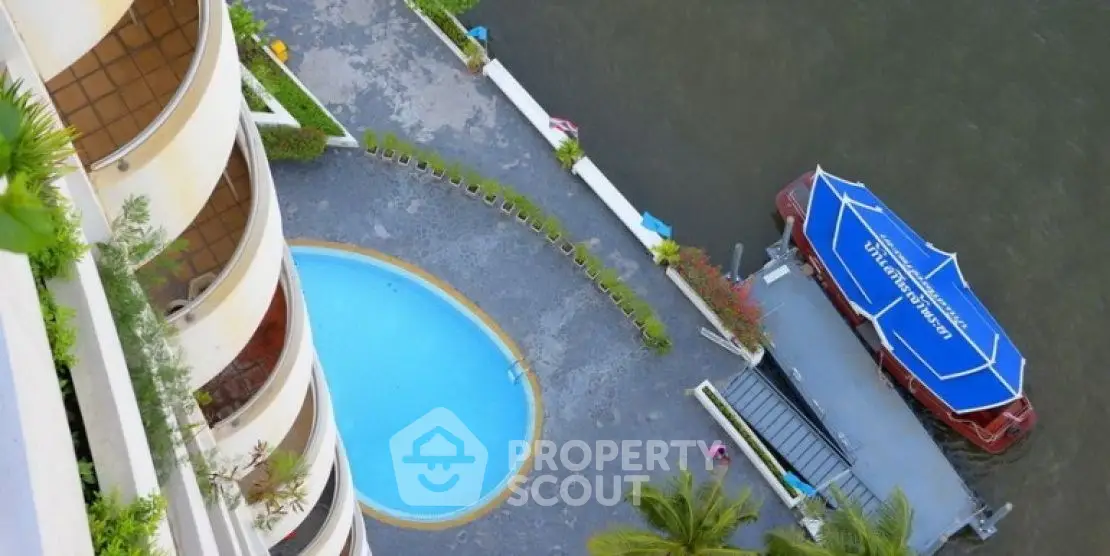 Stunning aerial view of riverside apartment with pool and private dock access.