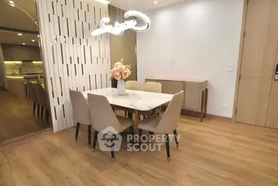Elegant dining area with modern lighting and wooden flooring in a stylish apartment.