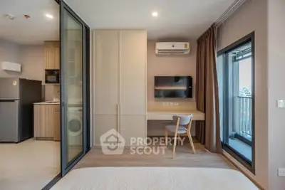 Modern studio apartment with open layout, featuring a compact kitchen and balcony access.