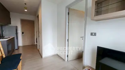 Modern apartment interior with open kitchen and cozy living area, featuring sleek wooden flooring and contemporary design.
