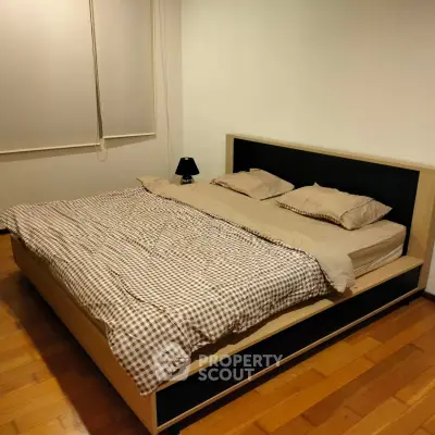 Cozy bedroom with wooden flooring and modern bed setup, perfect for relaxation.