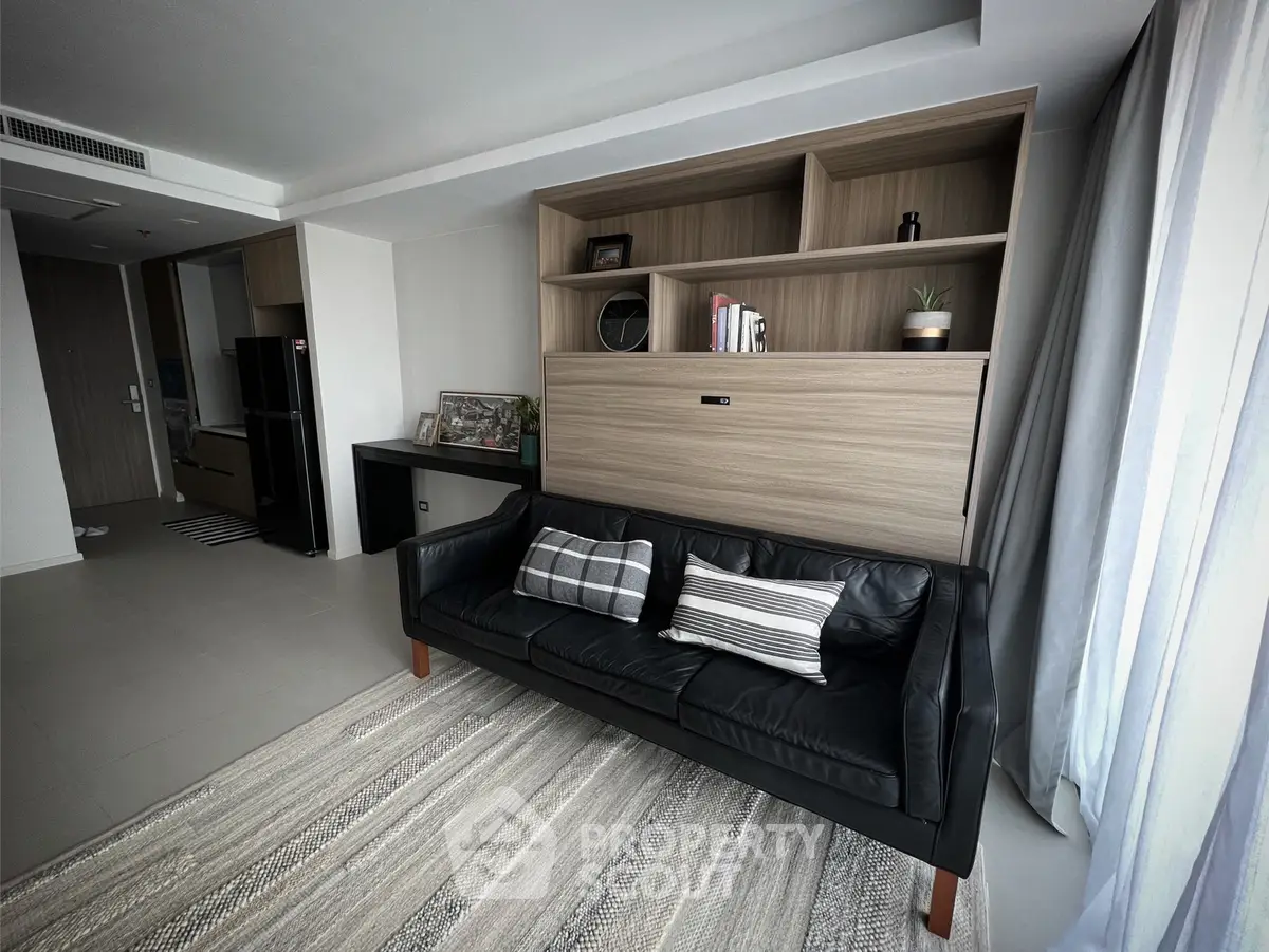 Modern living room with sleek black sofa and stylish shelving unit, perfect for urban living.