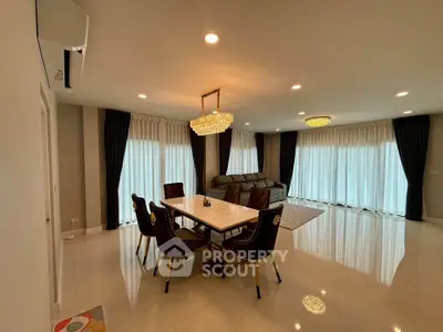 Spacious modern living room with elegant dining area and luxurious lighting fixtures.