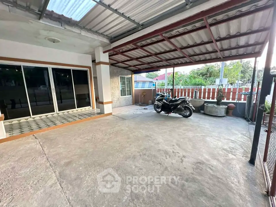 Spacious covered parking area with motorbike, ideal for secure vehicle storage.