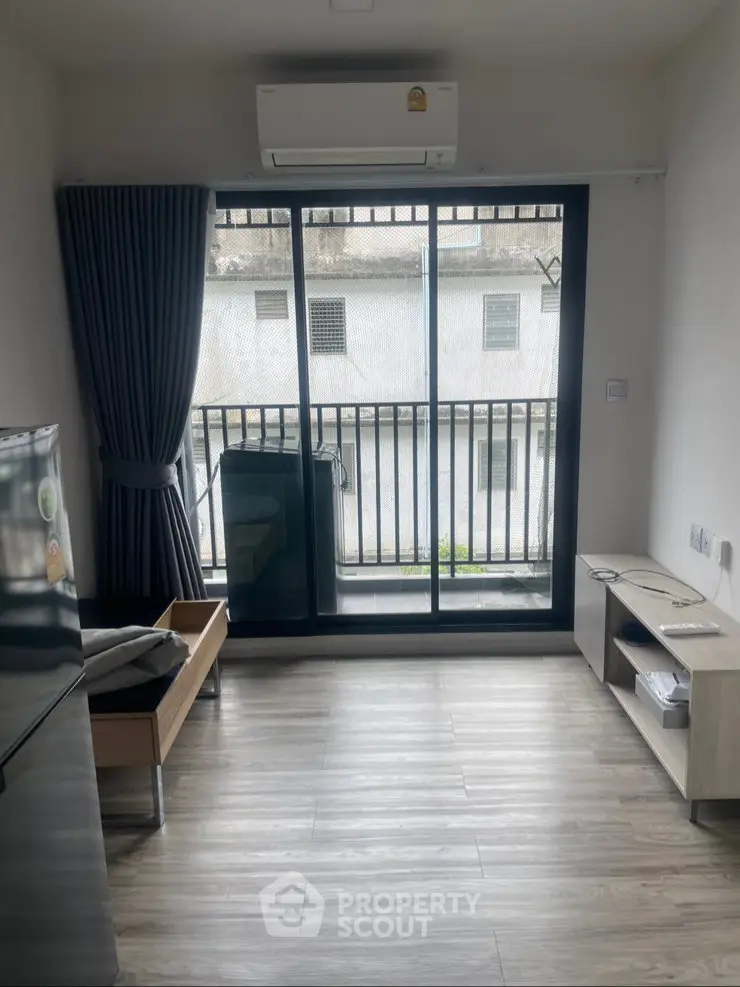 Modern living room with balcony, air conditioning, and sleek flooring in urban apartment.