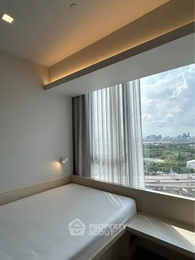 Modern bedroom with large window offering stunning city view and natural light.