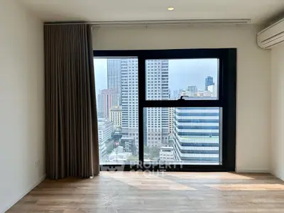 Modern apartment with large window offering stunning city view, featuring sleek flooring and elegant curtains.