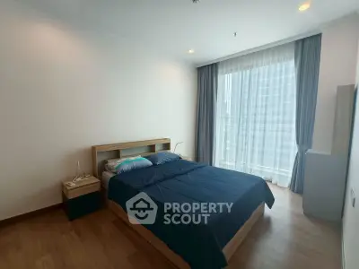 Spacious bedroom with modern furnishings and large window offering natural light.